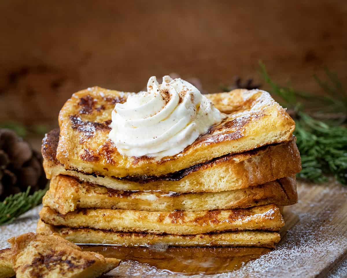 Stack of cut into Eggnog French Toast on a cutting board covered in confectioners sugar.