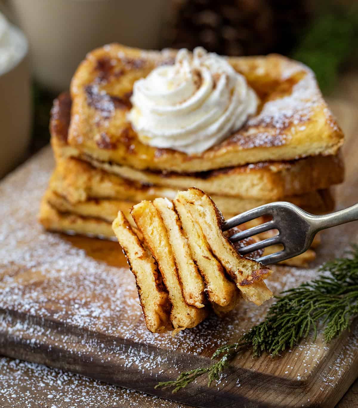 Stack of Eggnog French Toast that has been cut with pieces stacked on a fork in front of the stack.