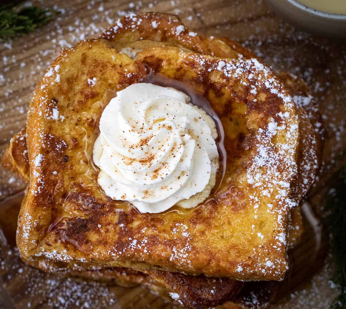 Stack of eggnog french toast with an Eggnog Whipped Cream topping.