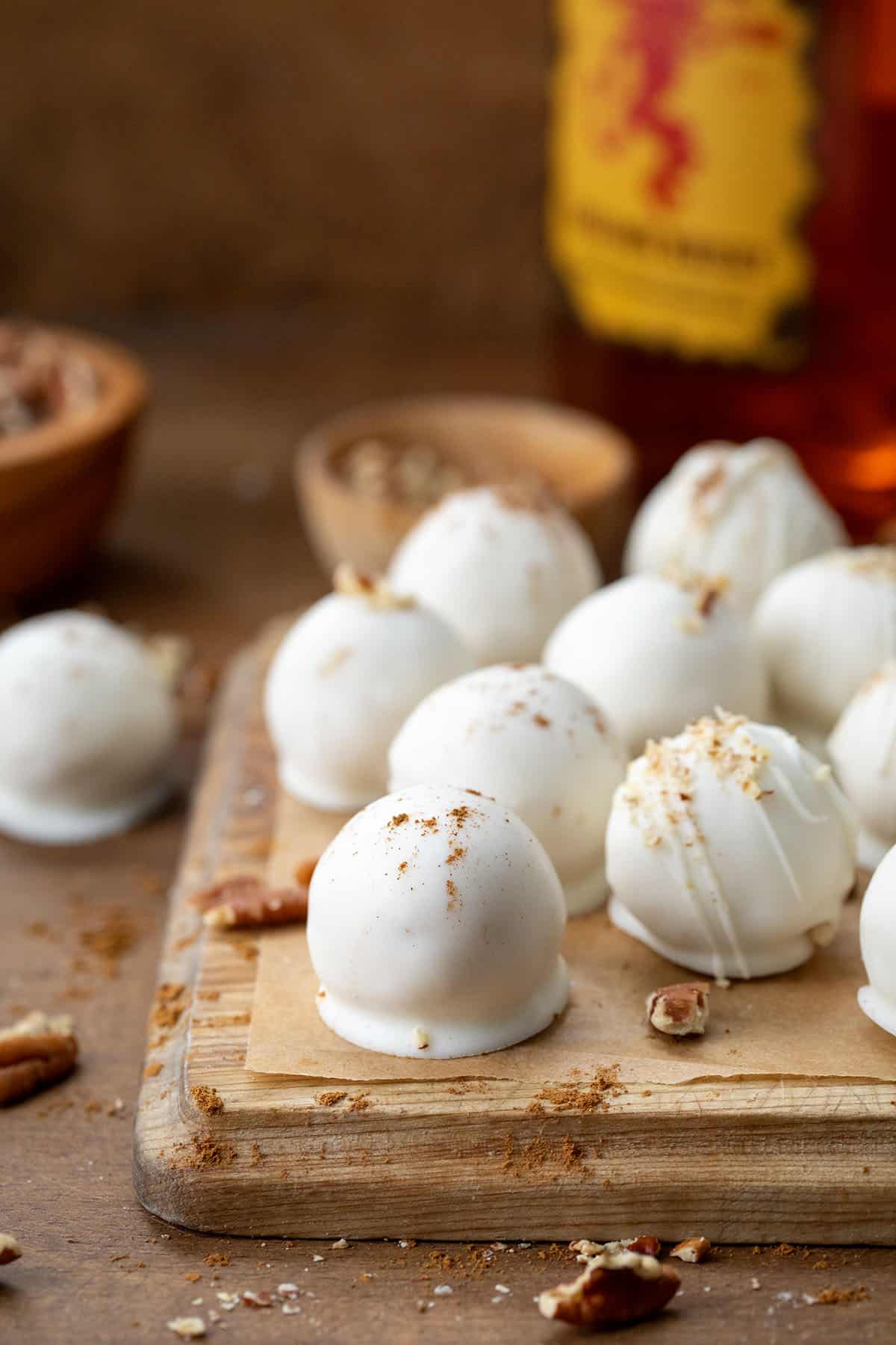 Fireball Truffles on a cutting board on a wooden table with a bottle of Fireball in the bakcground.