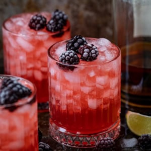 Glasses of Frosted Blackberry Bourbon Smash on a wooden table.