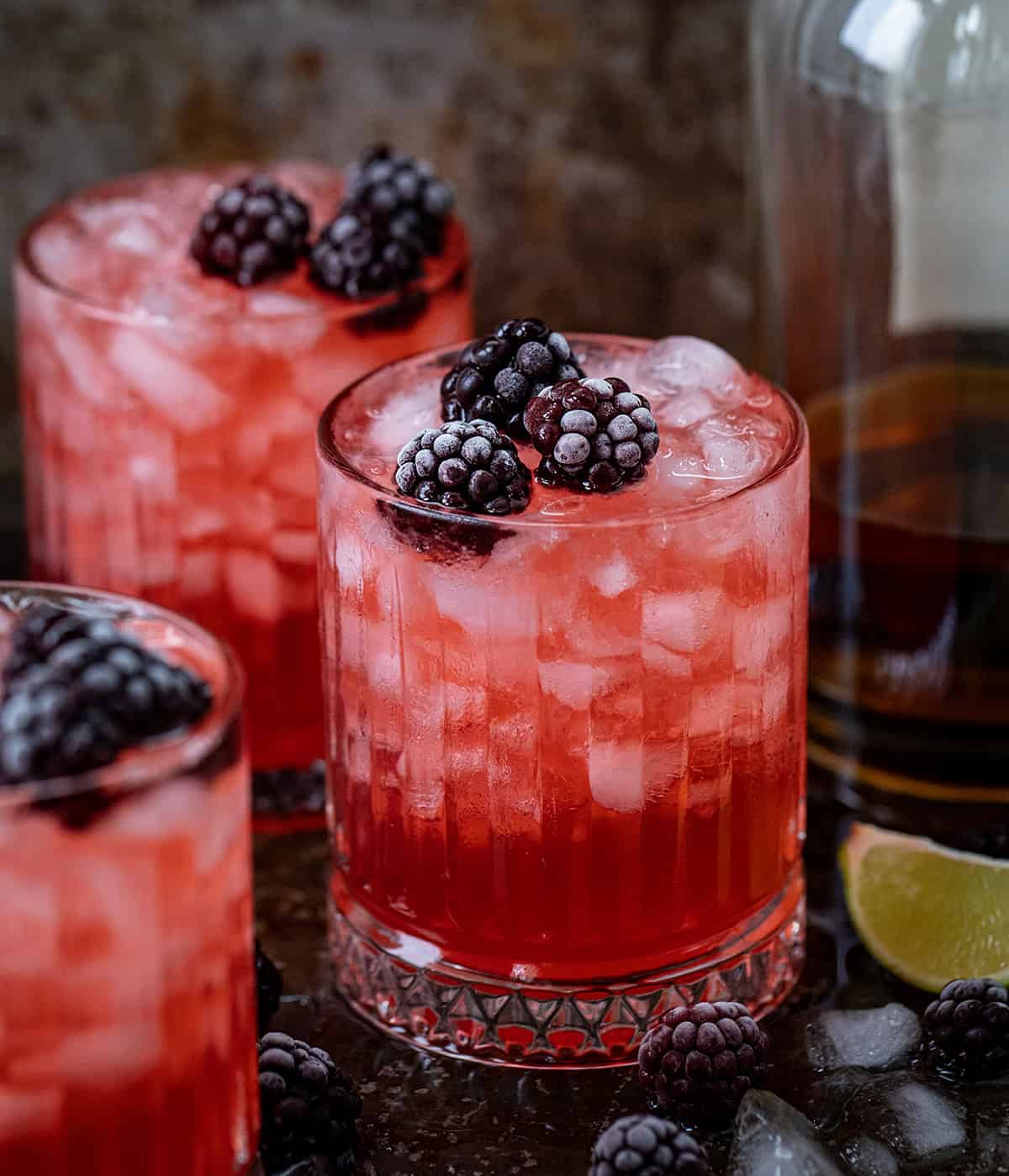 Glasses of Frosted Blackberry Bourbon Smash on a wooden table. 