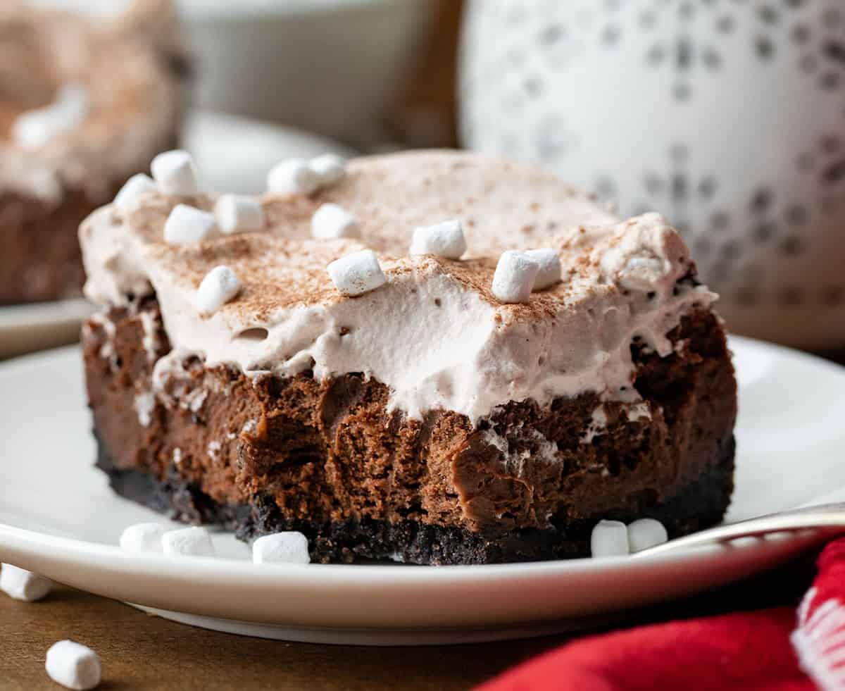 One Hot Chocolate Cheesecake Bar on a white plate with a bite removed showing texture.