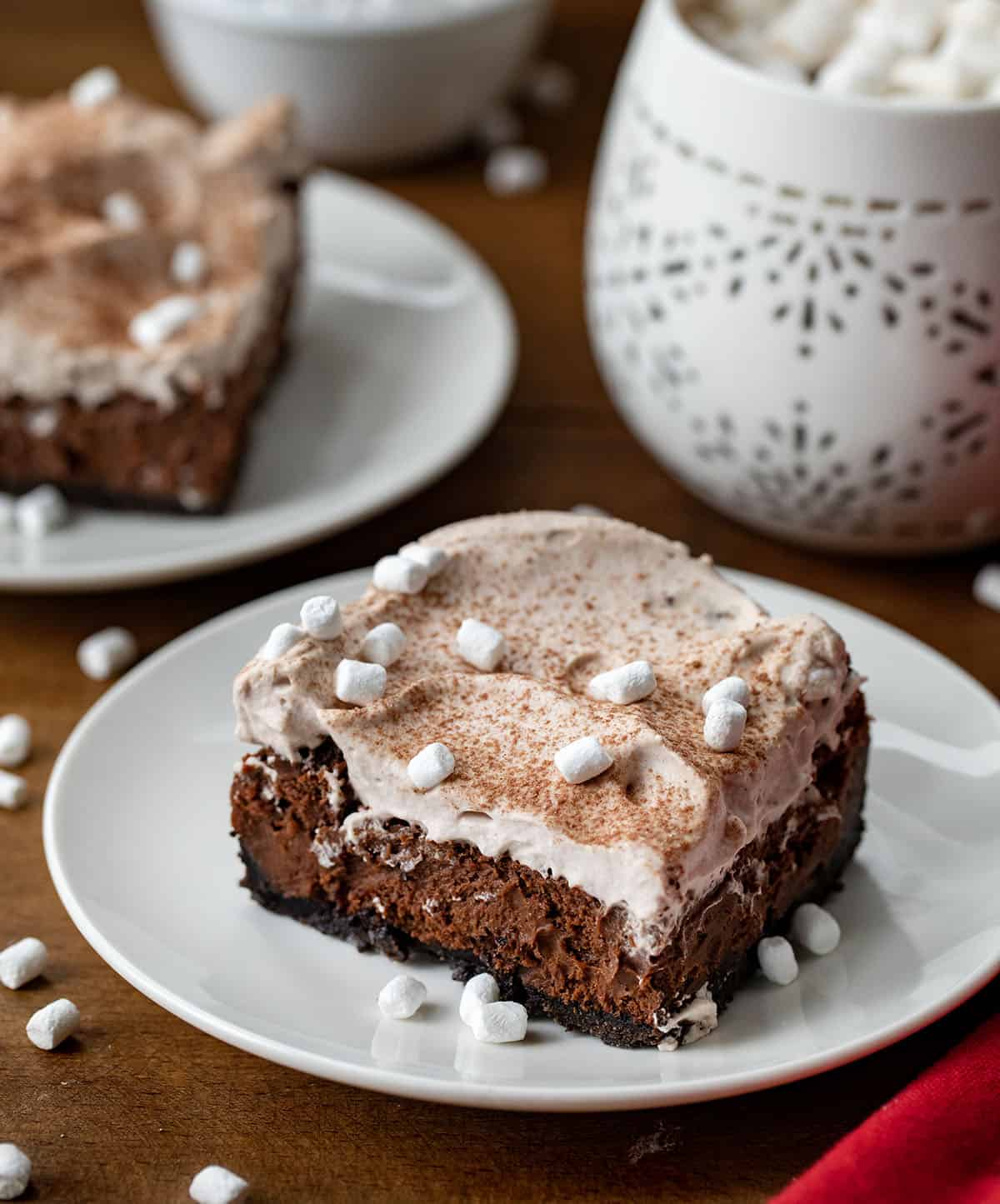 Hot Chocolate Cheesecake Bars on white plates on a wooden table.