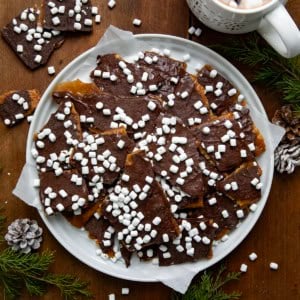 Plate of Hot Cocoa Christmas Crack on a white platter on a wooden table from overhead.