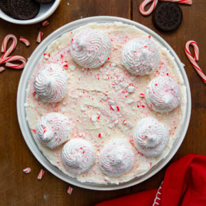 Whole No Bake Peppermint Cheesecake on a white platter on a wooden table from overhead.