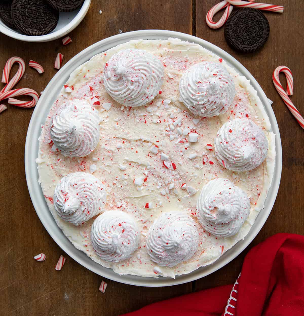 Whole No Bake Peppermint Cheesecake on a white platter on a wooden table from overhead.