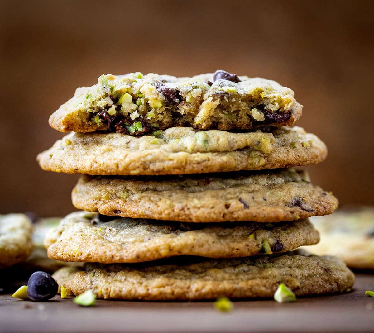 Stack of Pistachio Chocolate Chip Cookies with top cookie broken in half showing tender texture inside.