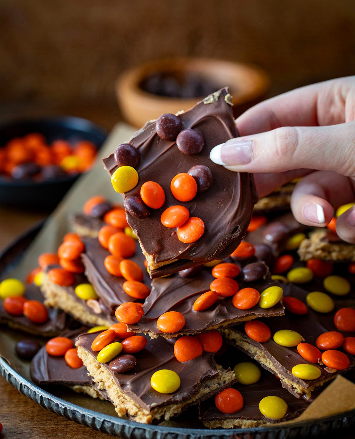 Hand holding a piece of Reese's Pieces Peanut Butter Bark.