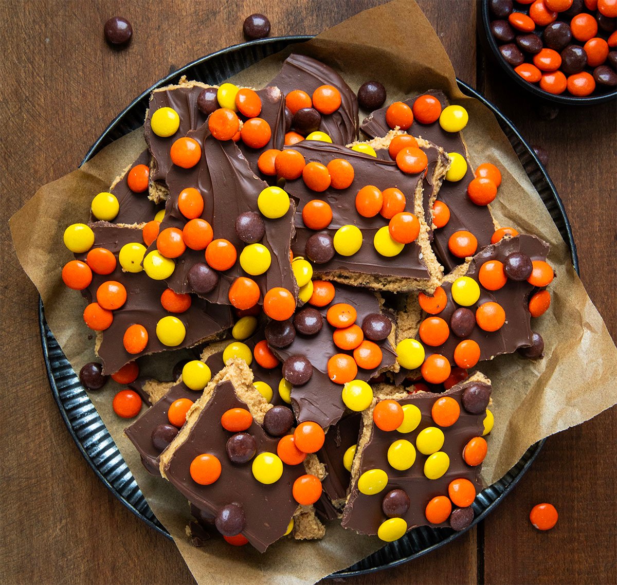 Reese's Pieces Peanut Butter Bark pieces on a tray on a wooden table from overhead.