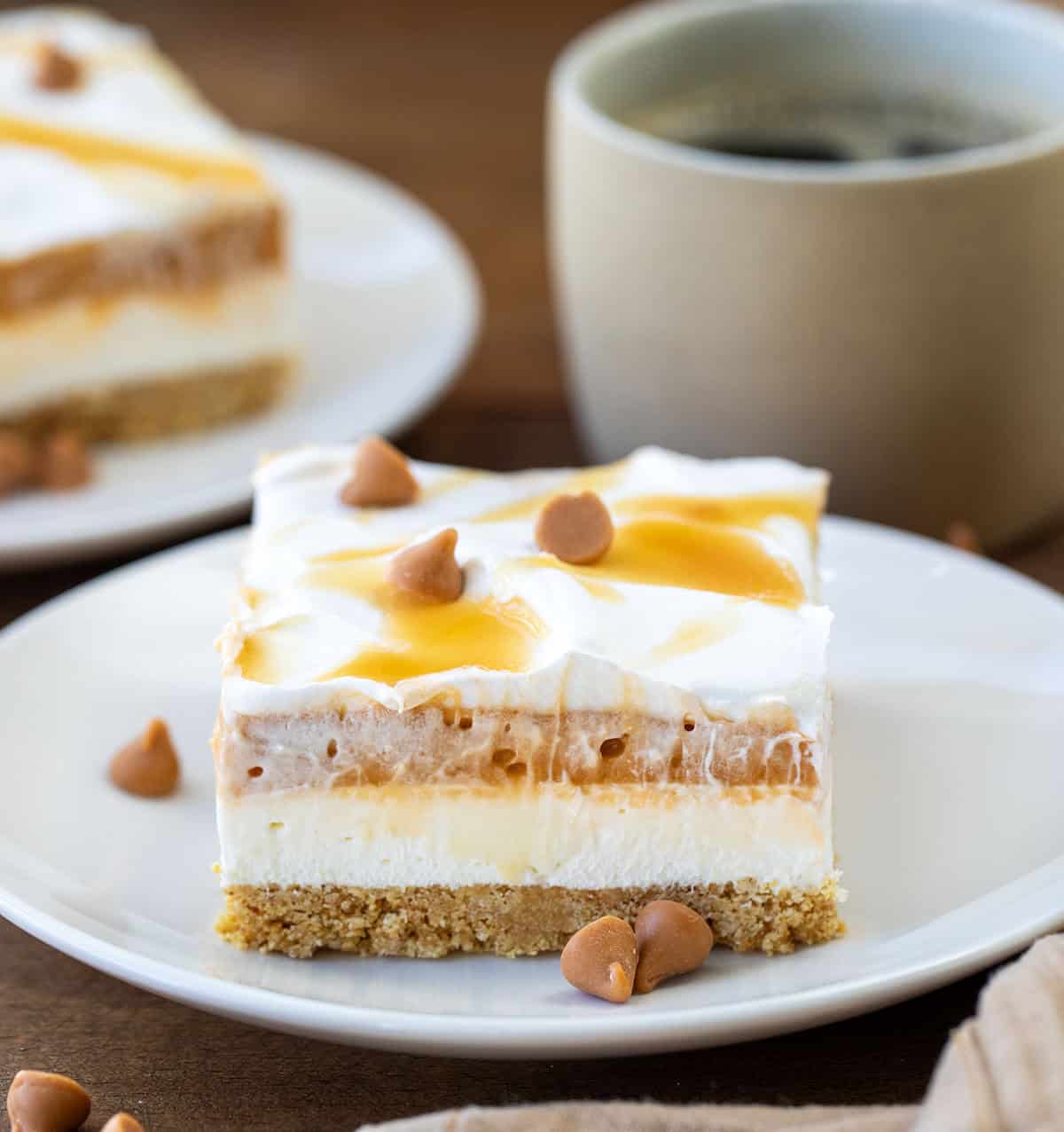 Pieces of Butterscotch Delight on white plates on a wooden table.