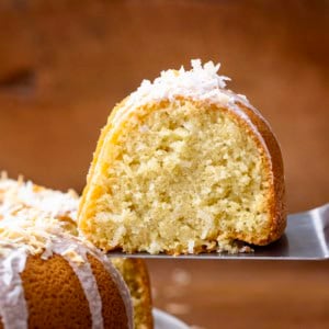 Cake server picking up a piece of Coconut Pound Cake from cake stand.