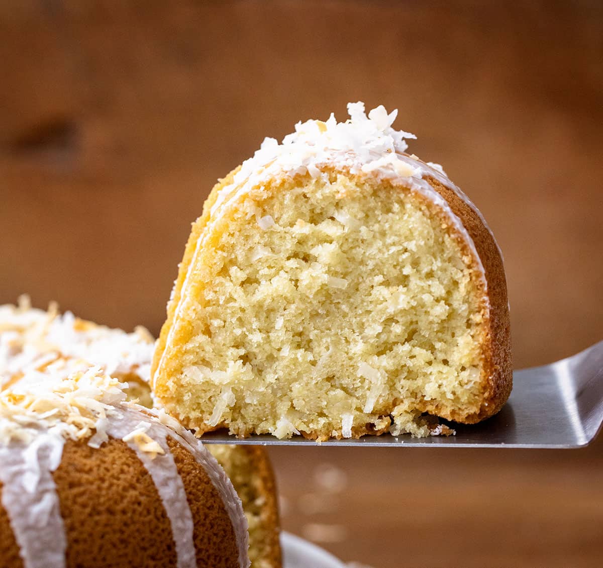 Cake server picking up a piece of Coconut Pound Cake from cake stand.