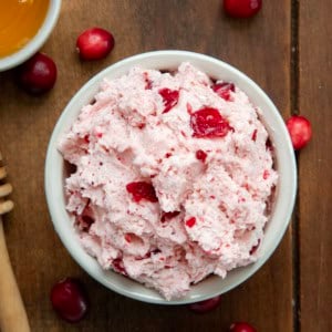 Looking down on a bowl of Cranberry Honey Butter on a wooden table.