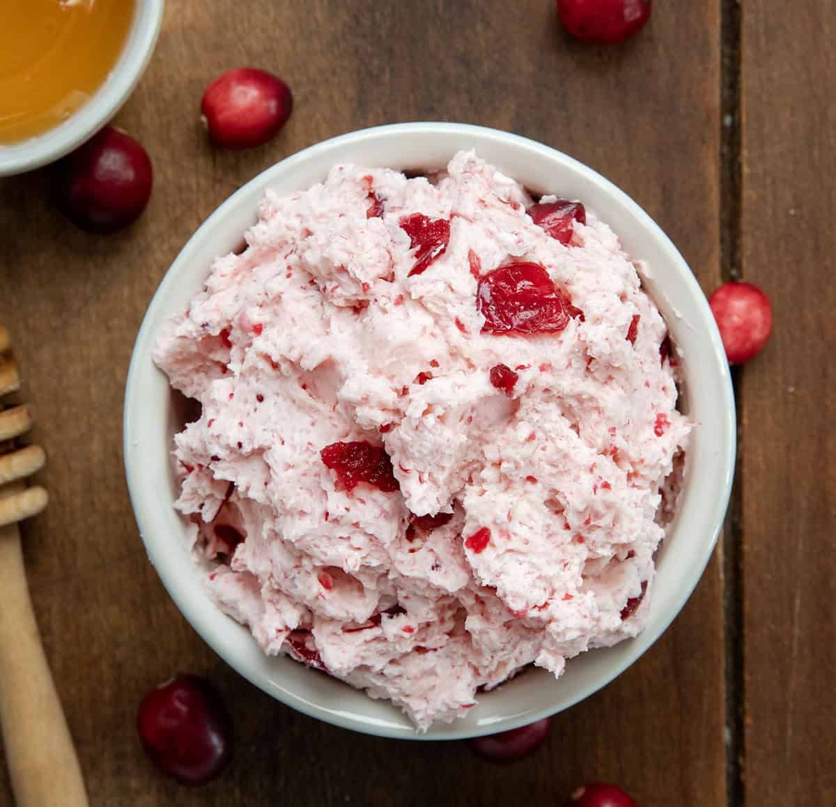 Looking down on a bowl of Cranberry Honey Butter on a wooden table.