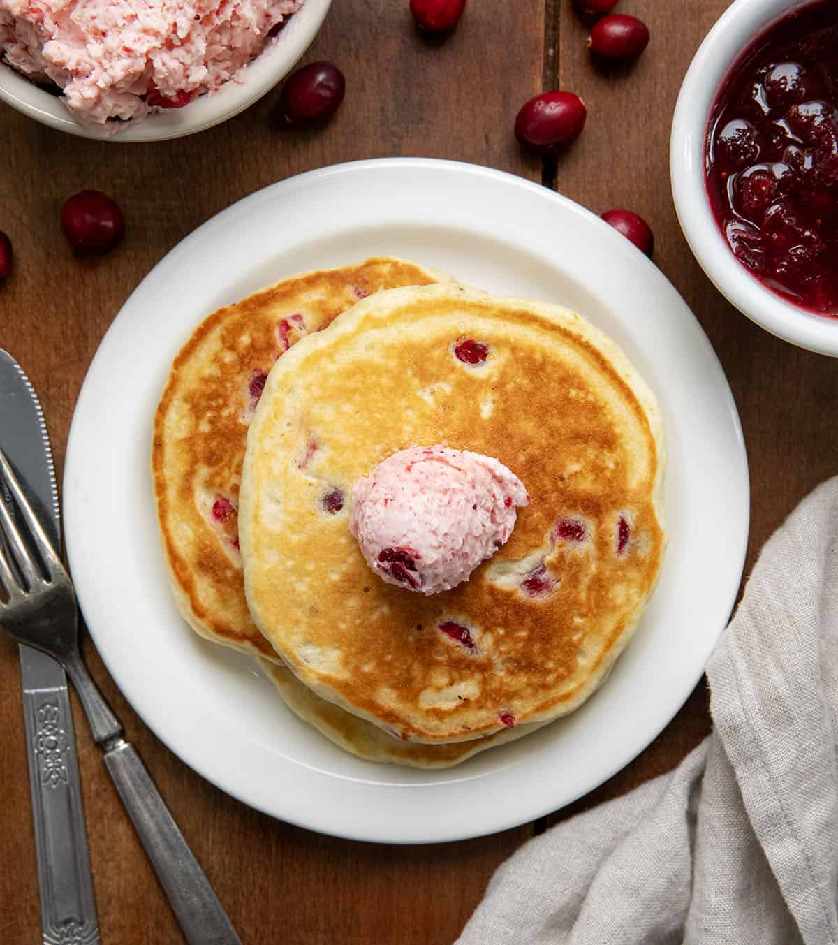 Looking down on a plate of Cranberry Orange Buttermilk Pancakes with cranberry butter.