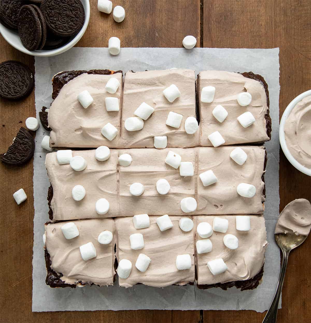 Hot Chocolate Lasagna Bars cut into pieces on a wooden table from overhead. 