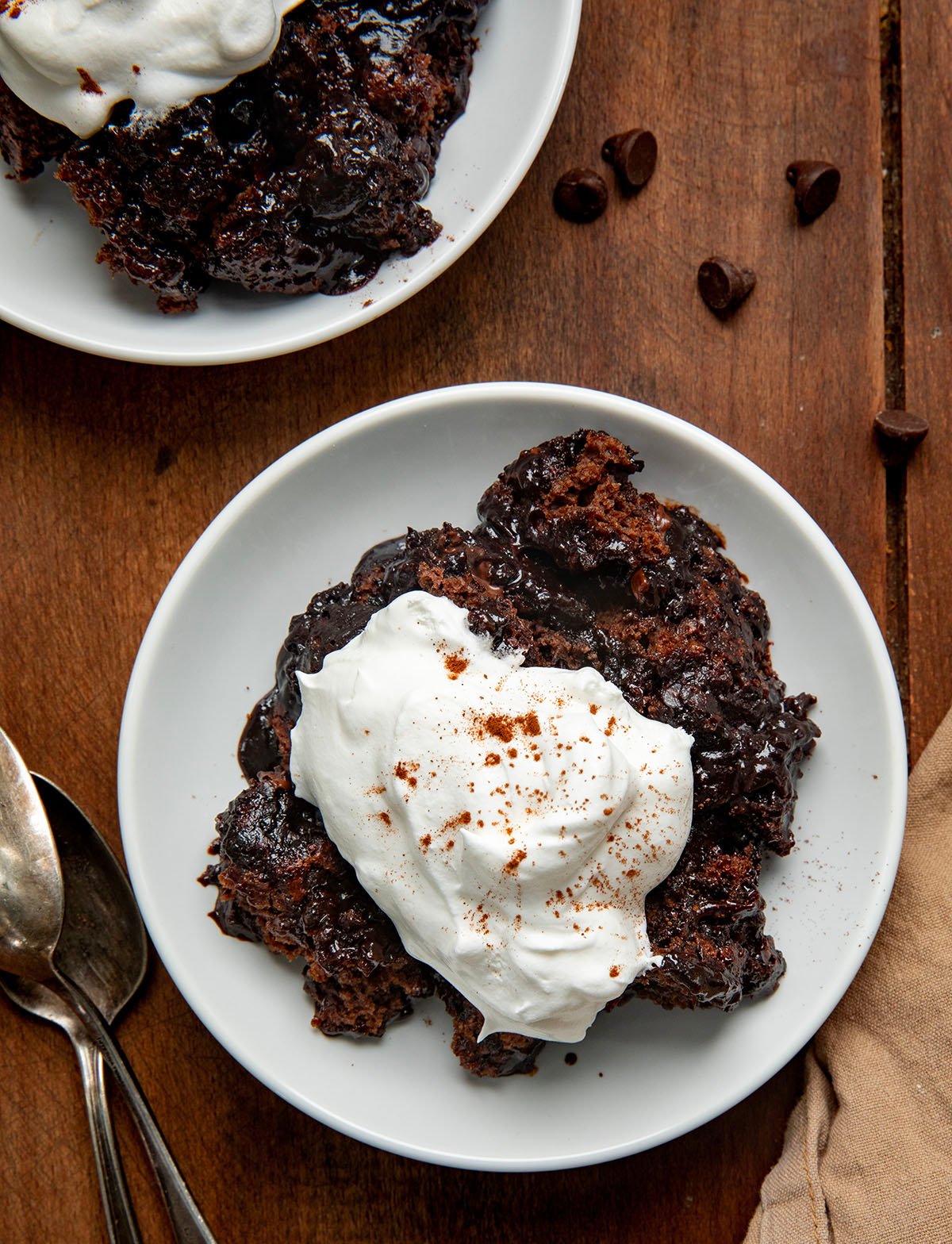 White plates with Hot Fudge Pudding Cake on them topped with whipped cream from overhead.