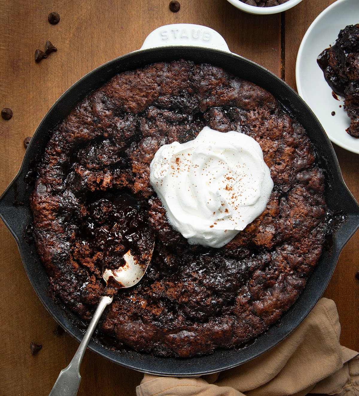 Skillet of Hot Fudge Pudding Cake with whipped cream and a spoon in the pan.