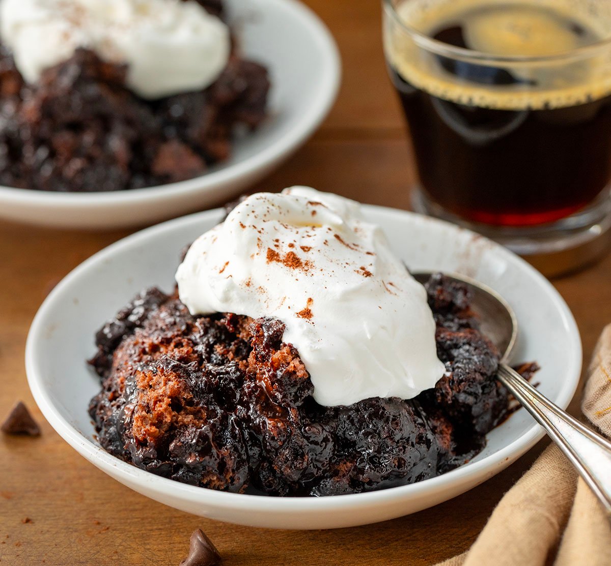 Plates of Hot Fudge Pudding Cake on a wooden table with a cup of coffee.