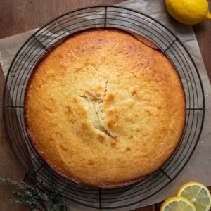 Olive Oil Cake on a rack on a wooden table from overhead with fresh lemon.