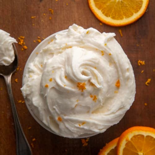 Rustic bowl of Orange Creamsicle Buttercream on a wooden table.