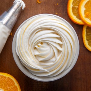 Bowl of piped Orange Creamsicle Buttercream on a wooden table from overhead.