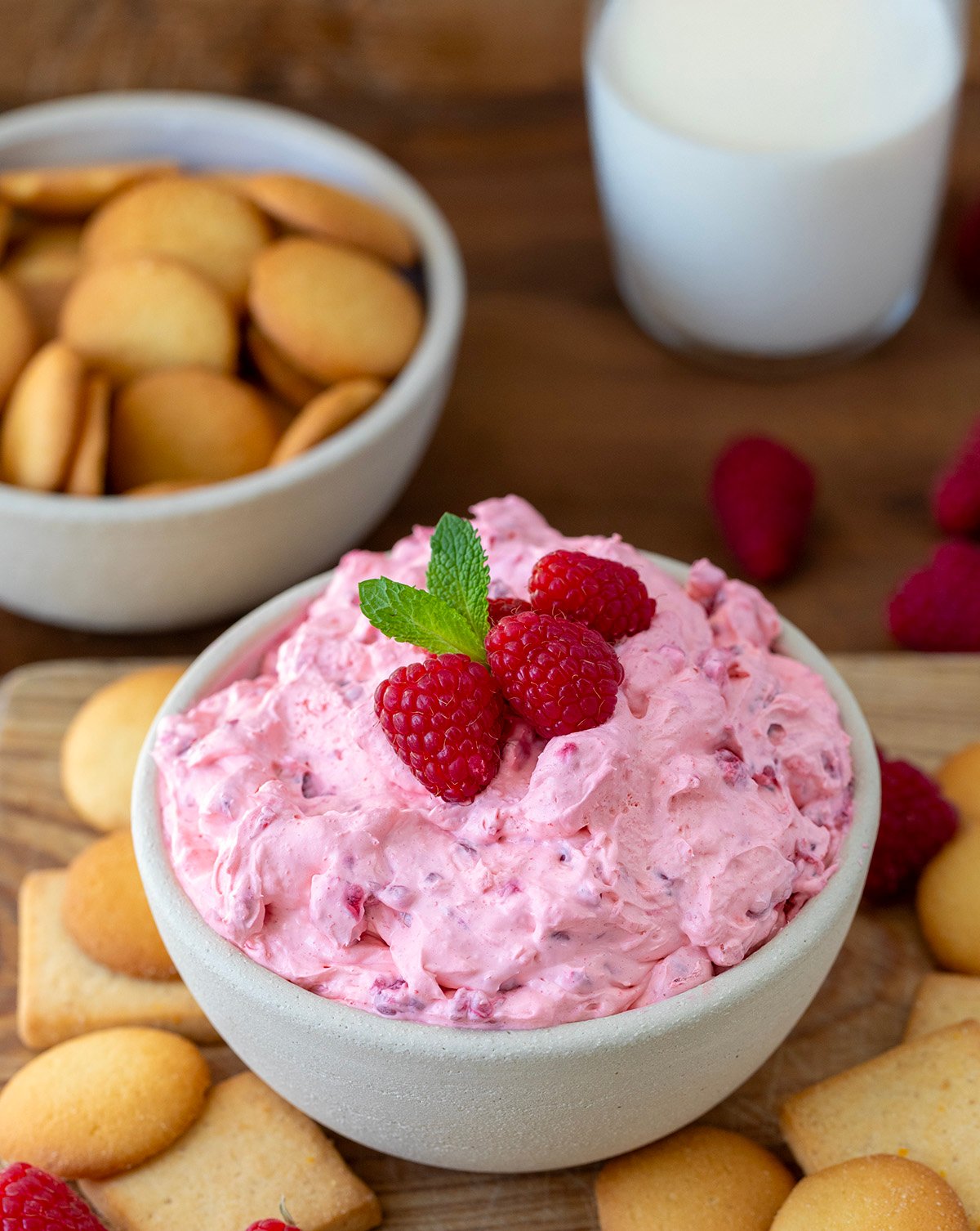 Bowl of Raspberry Cheesecake Dip on a wooden table with vanilla wafers.