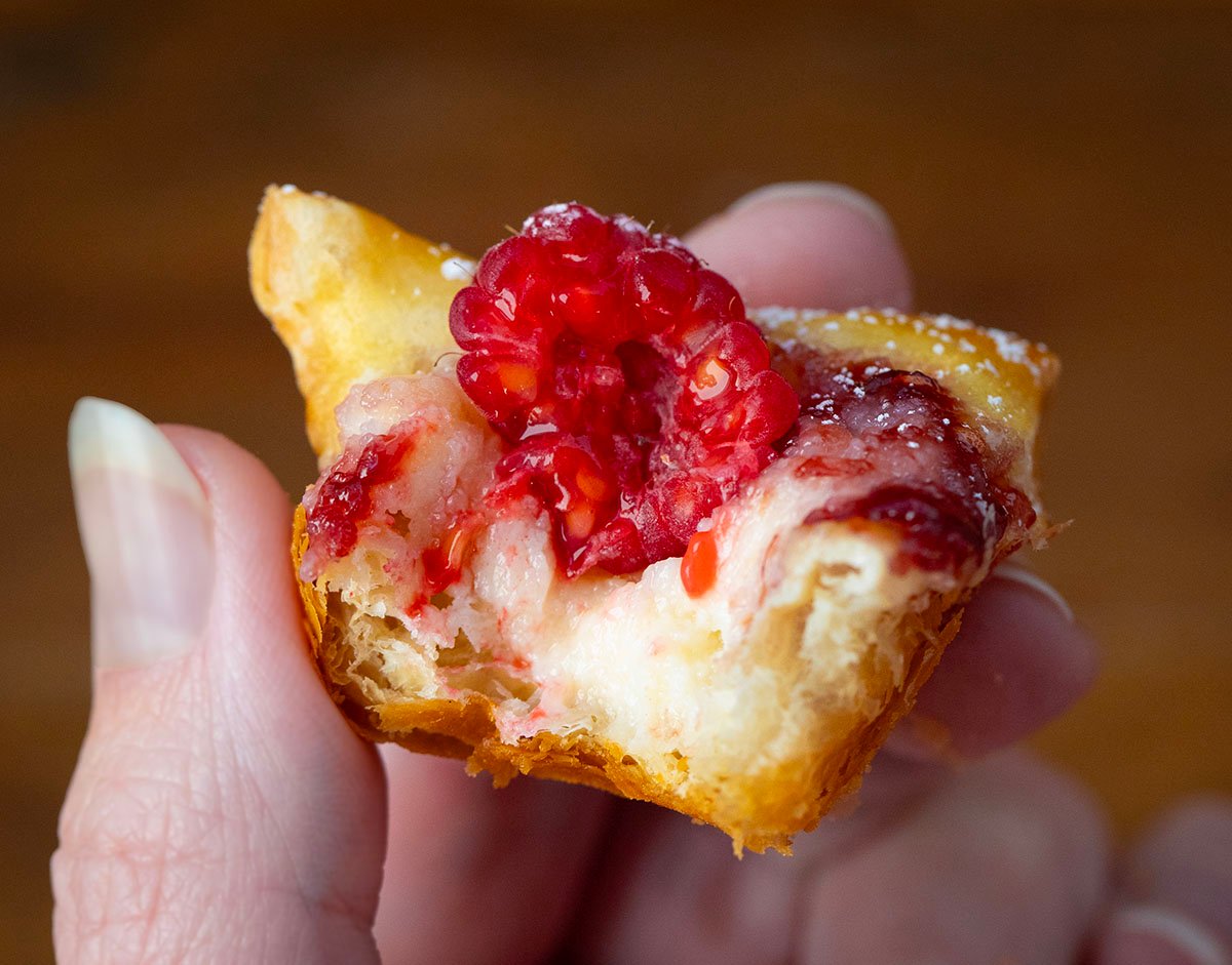 Hand holding a bit into Raspberry Cream Cheese Bite.