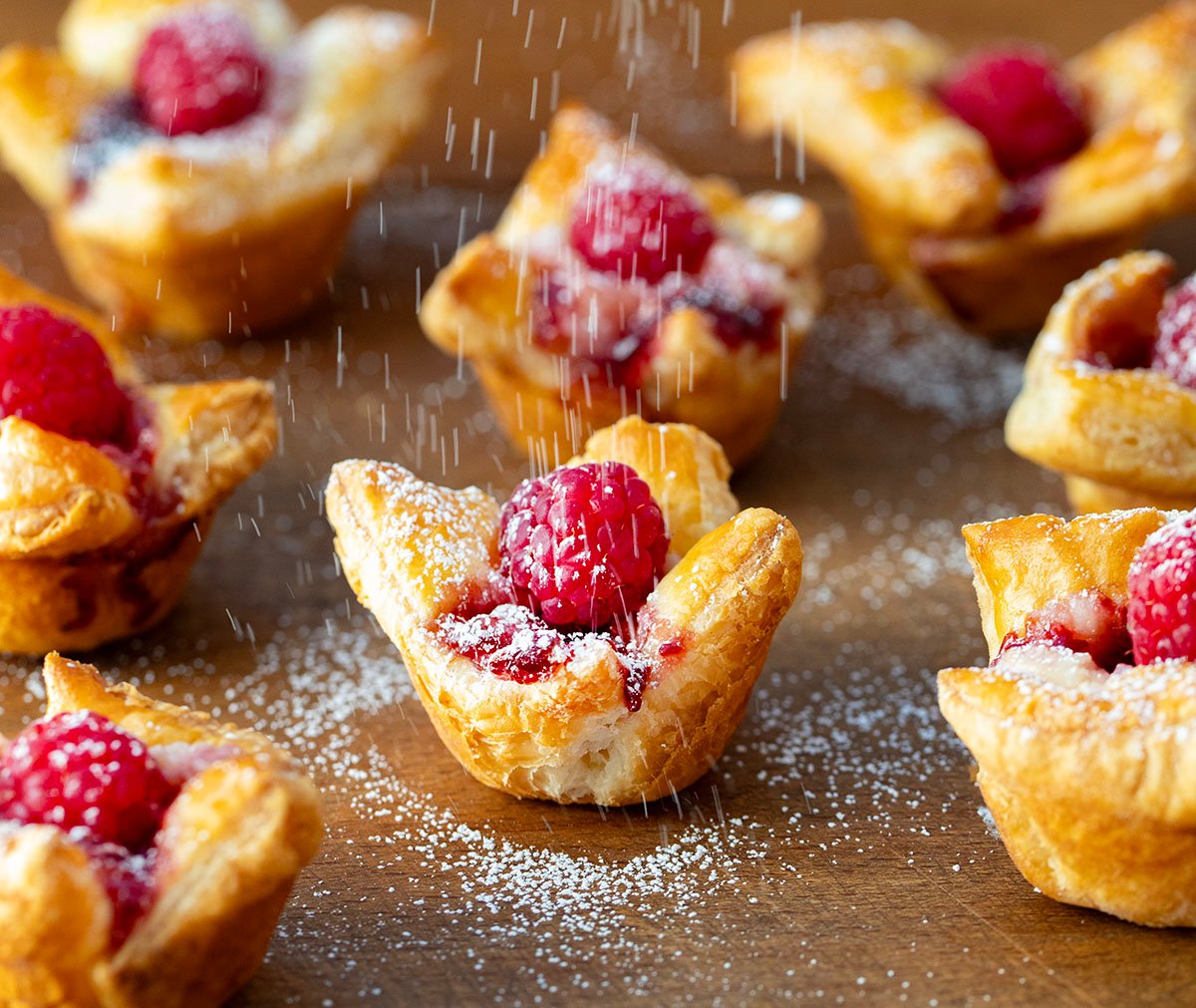 Dusting Raspberry Cream Cheese Bites with confectioners sugar.