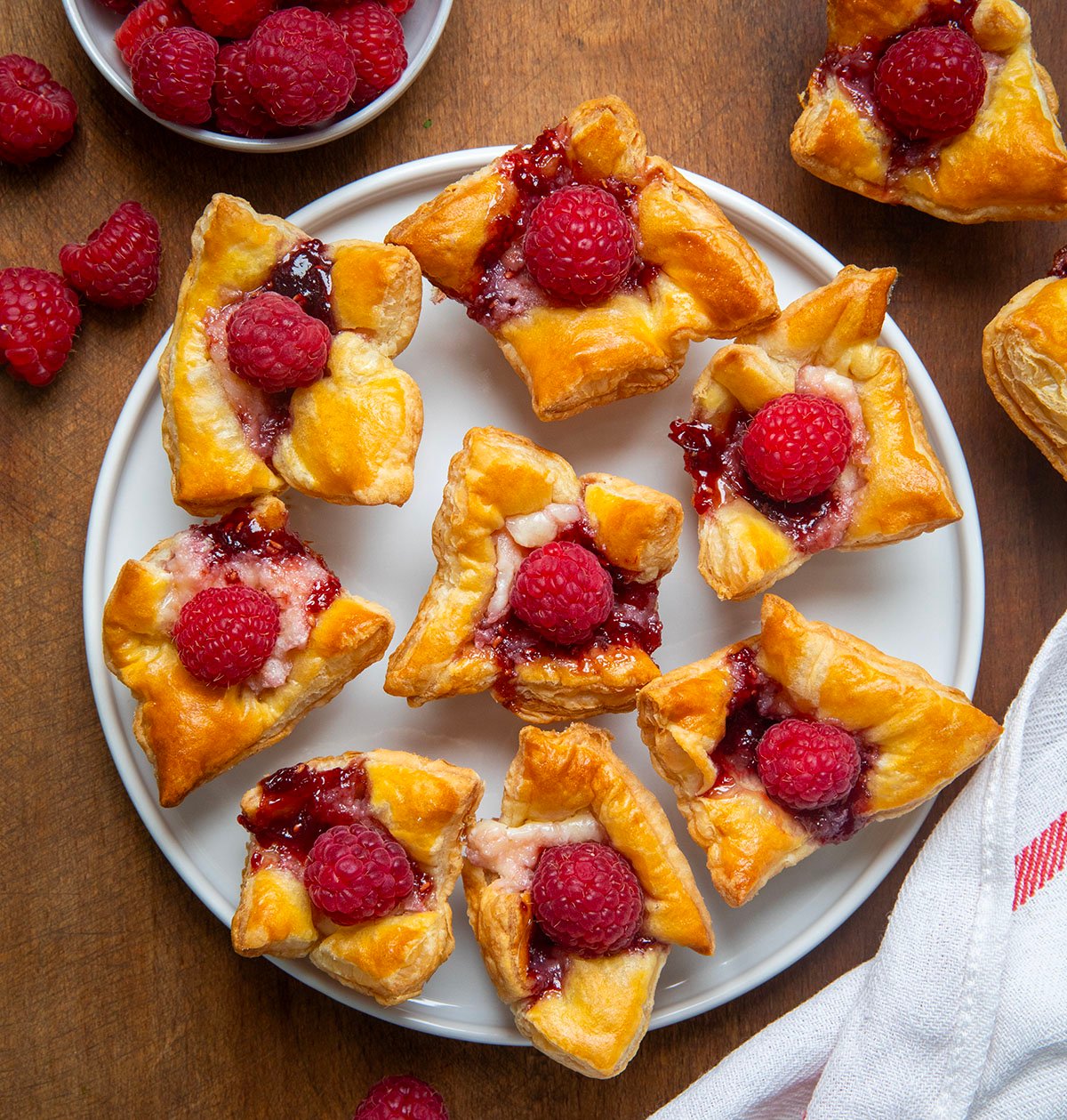 Raspberry Cream Cheese Bites on a white plate on a wooden table from overhead. 