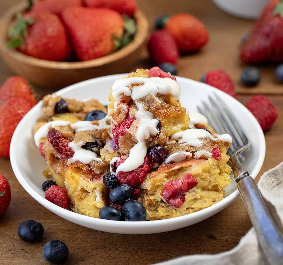 Bowl of Berries and Cream Overnight French Toast Bake on a wooden table close up.