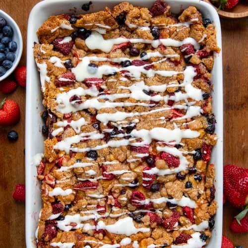 White pan filled with Berries and Cream Overnight French Toast Bake on a wooden table from overhead.