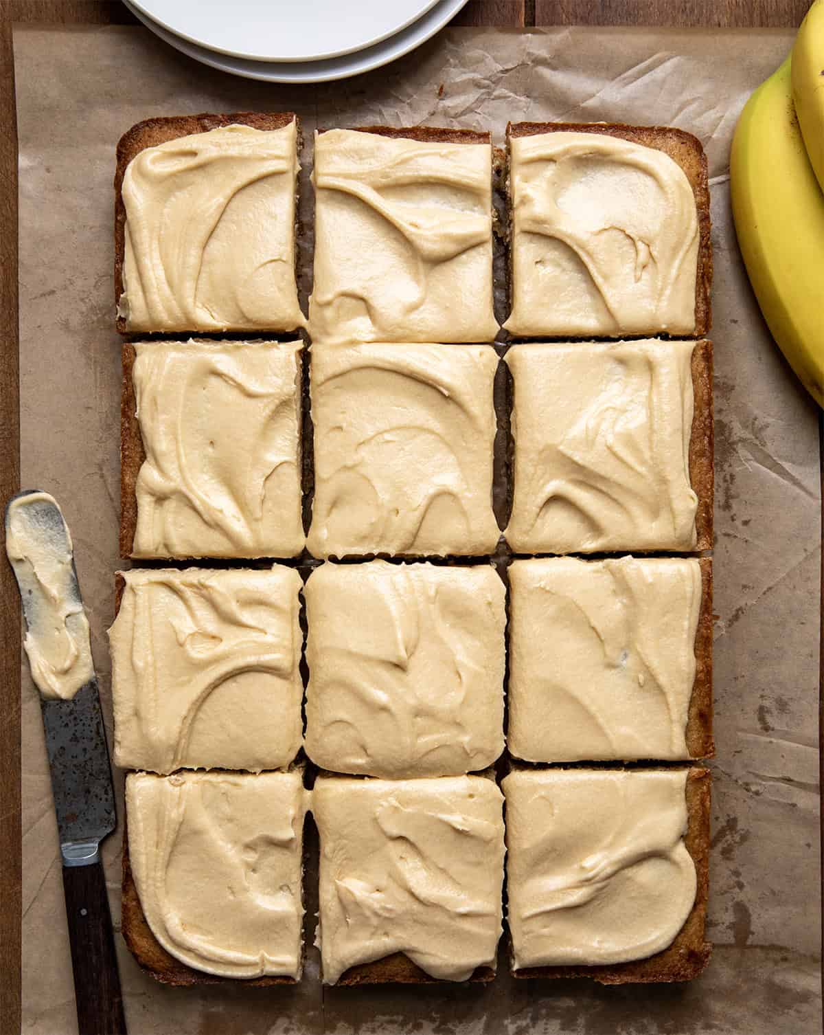 Browned Butter Banana Bars With Salted Caramel Buttercream cut into squares on a wooden table from overhead. 