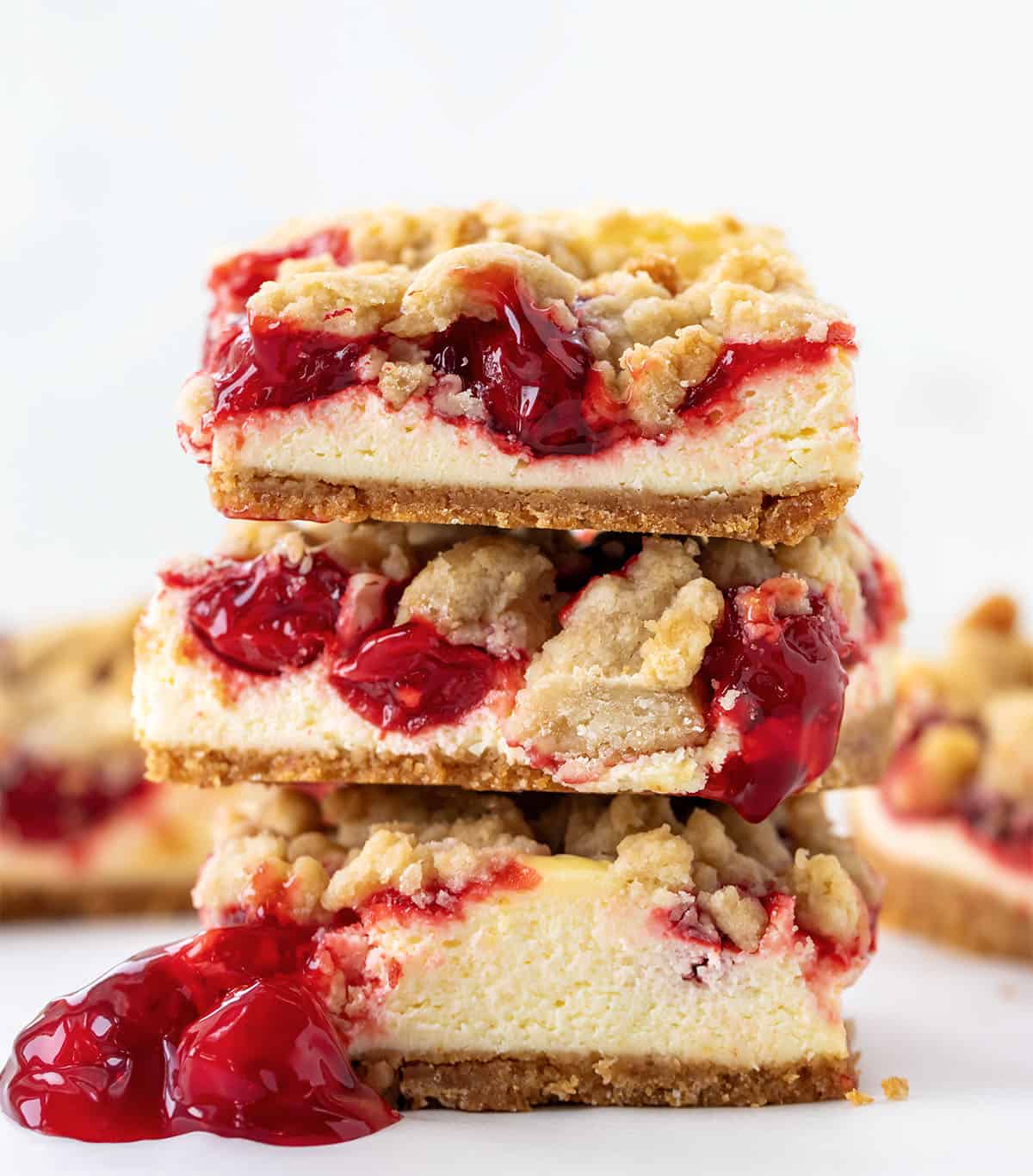 Stack of Cherry Almond Cheesecake Bars on a white table close up.