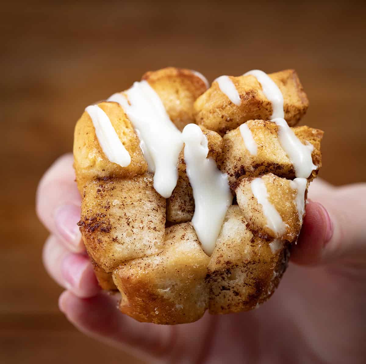 Hand holding a torn apart Cinnamon Roll Monkey Bread Muffin.