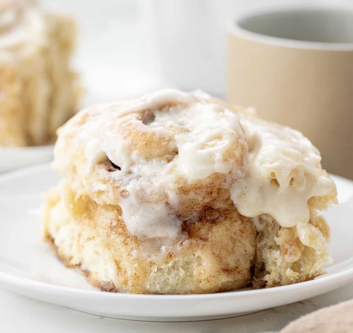 One Hour Cinnamon Roll on a plate with coffee in the background.