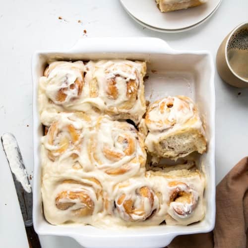 One Hour Cinnamon Rolls in a pan with a couple of rolls removed and one on its side in the pan.