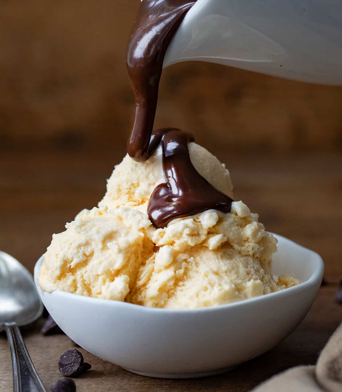 Pouring Peanut Butter Hot Fudge over vanilla ice cream.