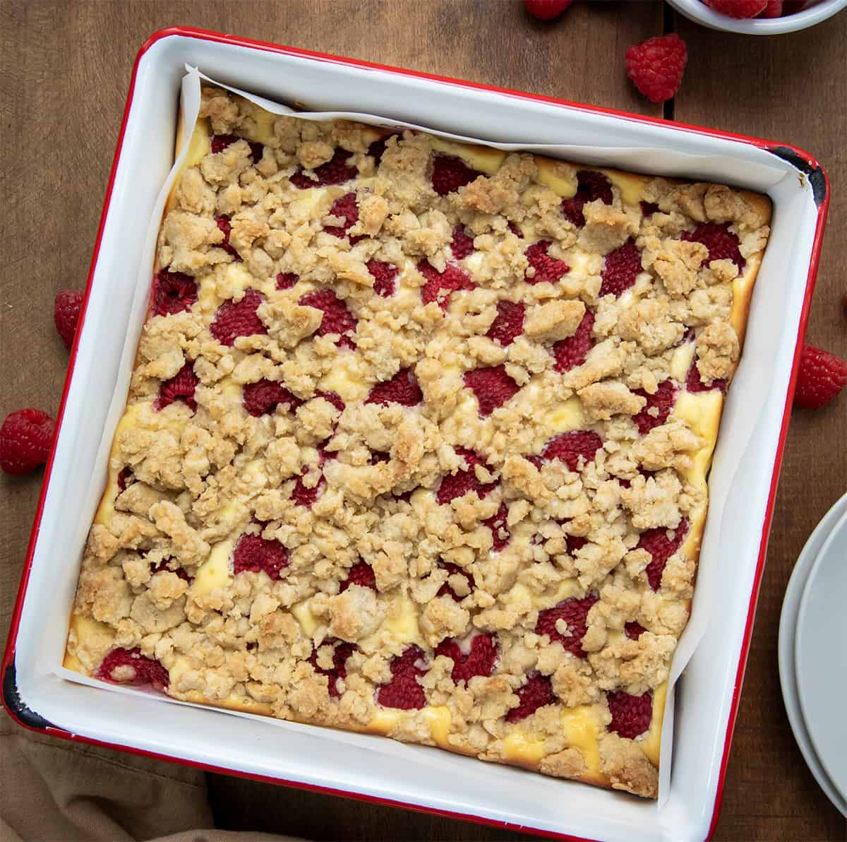 Pan of Raspberry Cheesecake Bars on a wooden table from overhead. 