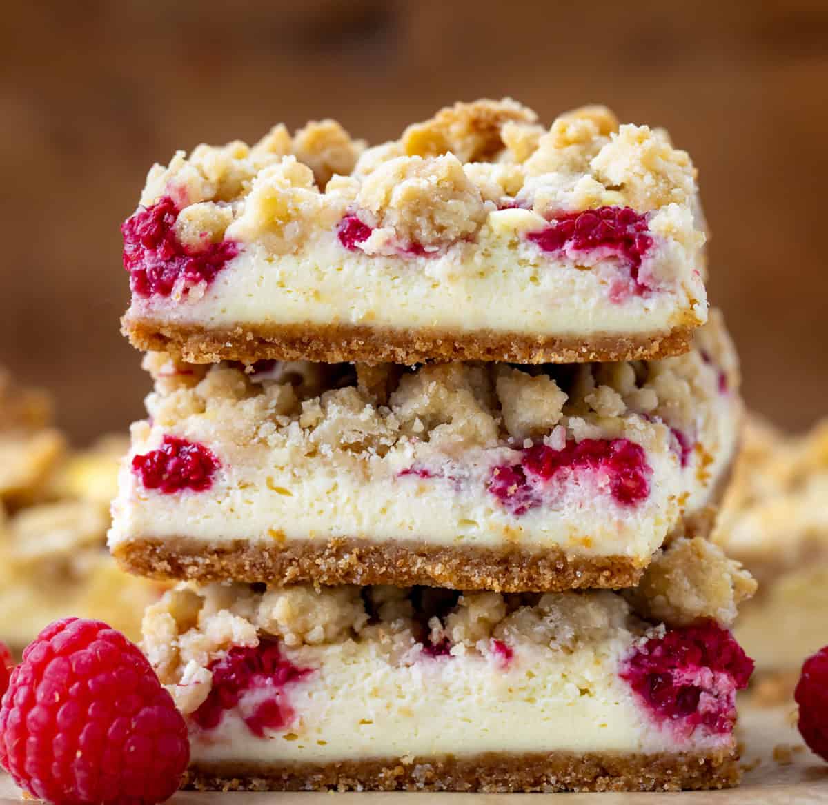 Stack of Raspberry Cheesecake Bars on a wooden table very close up.