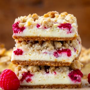 Stack of Raspberry Cheesecake Bars on a wooden table very close up.