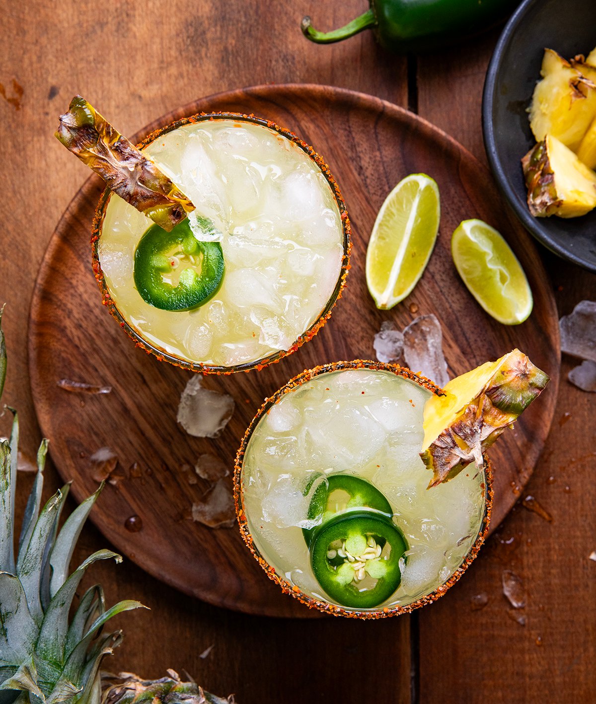 Glasses of Spicy Pineapple Margarita on a wooden table from overhead.