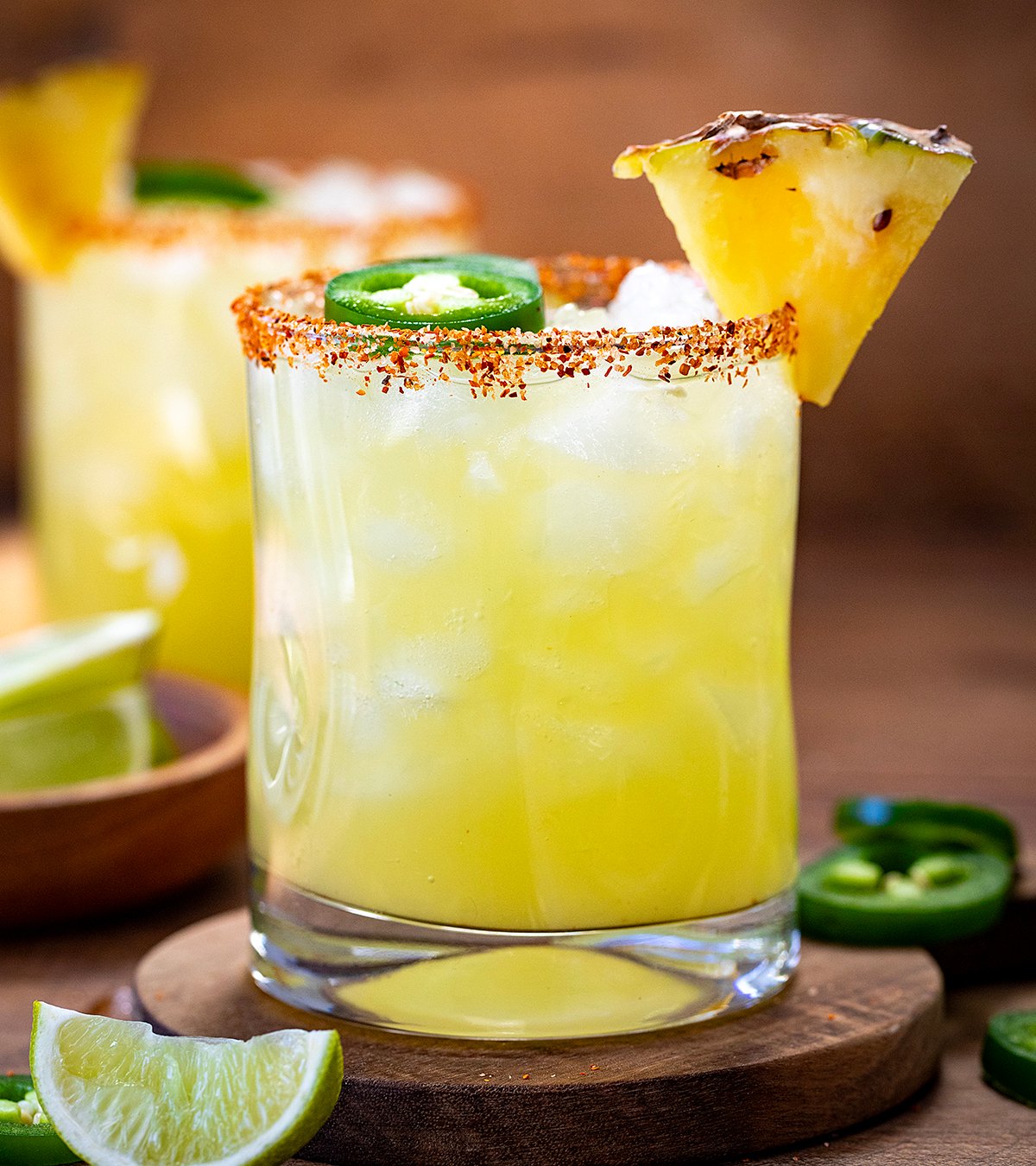 Close up of glasses of Spicy Pineapple Margarita on a wooden table. 