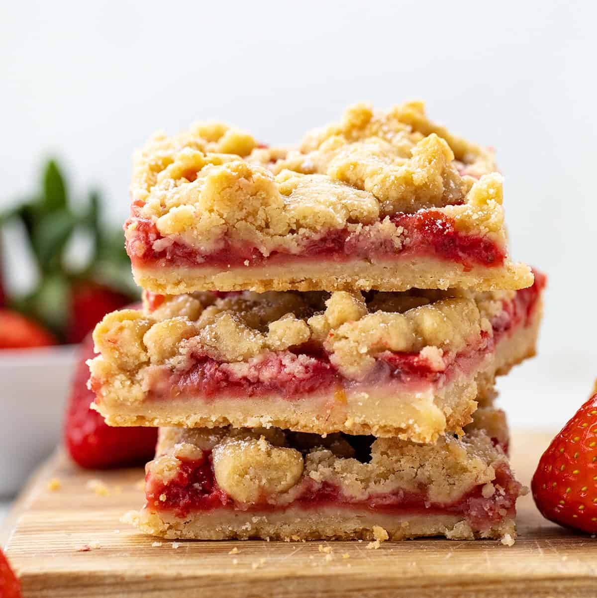 Stacked Strawberry Crumble Bars on a cutting board on a white table close up.