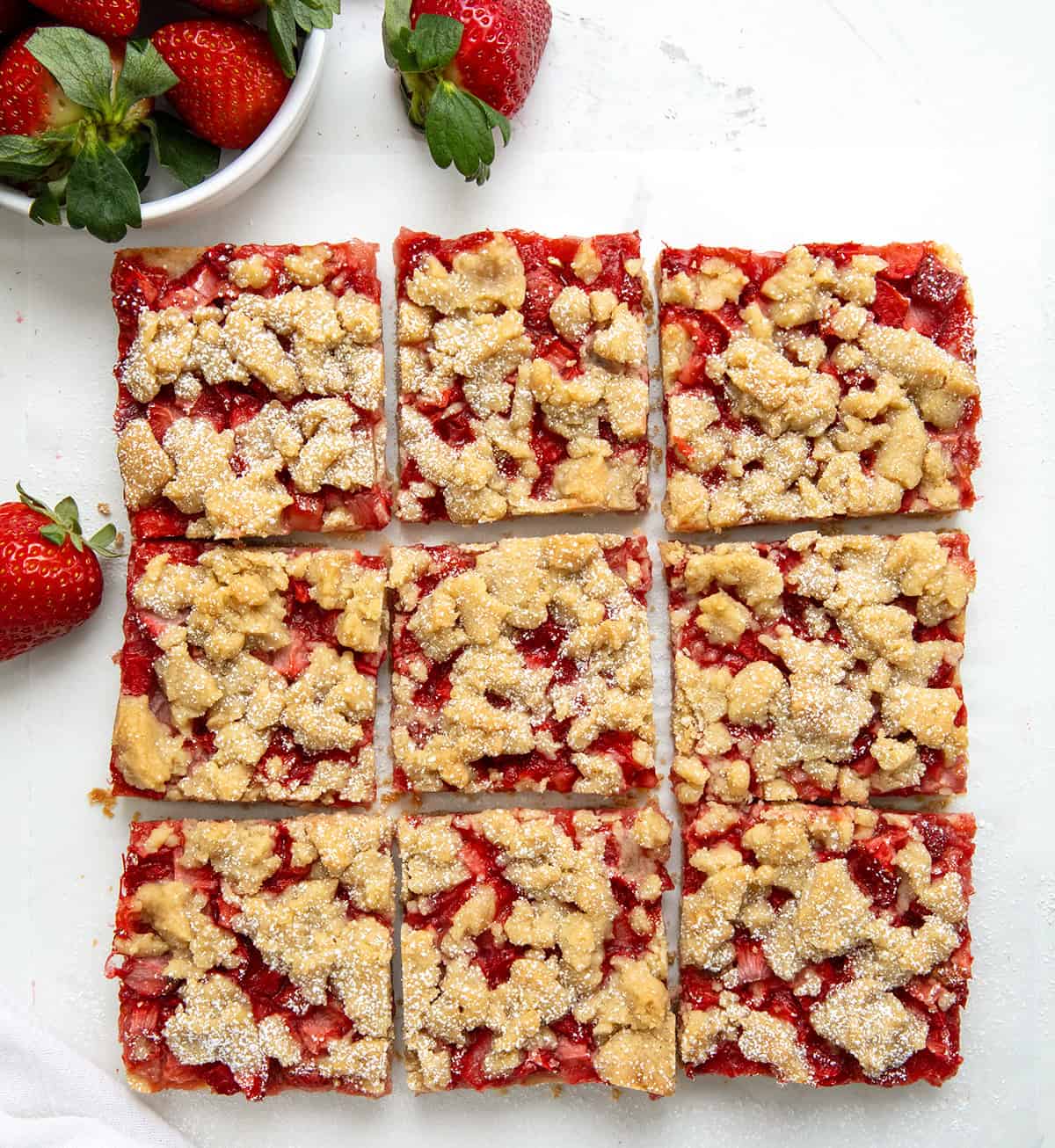 Strawberry Crumble Bars cut into squares on a white table from overhead. 