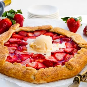 Strawberry Galette on a white table with wine and fresh strawberries.