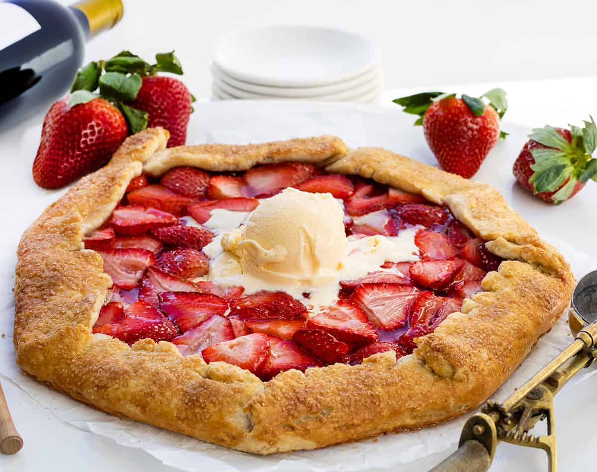 Strawberry Galette on a white table with wine and fresh strawberries.