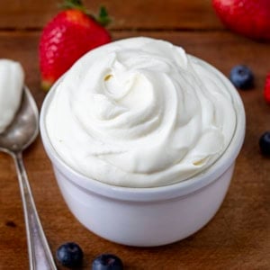 Bowl of Whipped Cream Cheese Frosting on a wooden table close up.