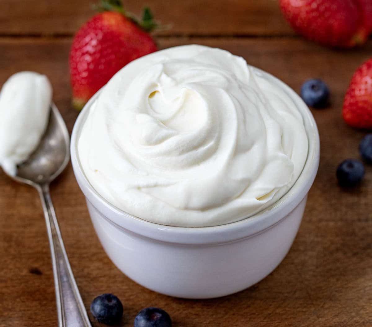 Bowl of Whipped Cream Cheese Frosting on a wooden table close up. 